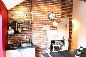a kitchen with a brick wall with a clock at Le Tripode-Hypercentre au calme et atypique in Nantes