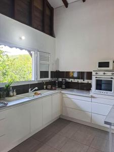 eine Küche mit weißen Schränken, einem Fenster und einem Herd in der Unterkunft Villa Tourmaline in Le Lorrain