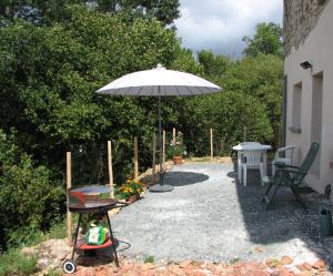 eine Terrasse mit Sonnenschirm, Grill und Tisch in der Unterkunft Tavaud in Dournazac