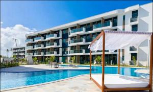 a hotel with a swimming pool in front of a building at Makia beach experience 315A Kay in Porto De Galinhas