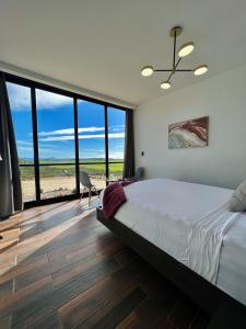 - une chambre avec un lit et des baies vitrées dans l'établissement NUMA Wine Suites, à Ensenada