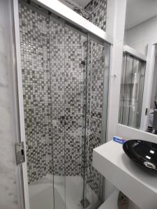 La salle de bains est pourvue d'une douche en verre et d'un lavabo. dans l'établissement Apartamento inteiro com área e garagem privativa, à Belo Horizonte