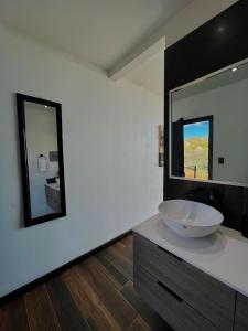 La salle de bains est pourvue d'un lavabo et d'un grand miroir. dans l'établissement NUMA Wine Suites, à Ensenada