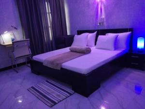 a bedroom with a large bed with purple lighting at DIVINE GRACE RESIDENCE INN in Agblangandan