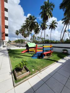 um parque infantil com bancos coloridos num parque com palmeiras em Cobertura Duplex Beira Mar 3 quartos em Maceió