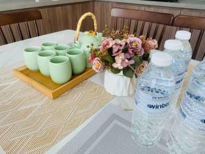 uma mesa com um ramo de flores e garrafas de água em 【森林城市高尔夫】度假式双层别墅民宿 em Gelang Patah