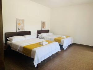 zwei Betten in einem Hotelzimmer mit weißen Wänden in der Unterkunft 【森林城市高尔夫】度假式双层别墅民宿 in Gelang Patah