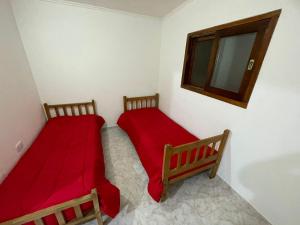 two beds in a room with red sheets and a mirror at casa de campo in Punta Indio