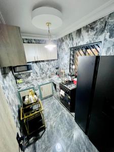 a kitchen with marble walls and a black refrigerator at The Jumeirah Guest Home in Yaoundé