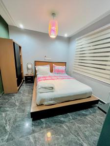 1 dormitorio con 1 cama grande y TV en The Jumeirah Guest Home, en Yaoundé