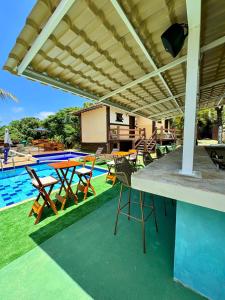 eine Terrasse mit Tischen und Stühlen neben einem Pool in der Unterkunft Estrelamar Ferradura Pousada Restaurante & Spa in Búzios