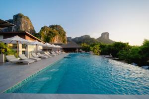a swimming pool with chairs and mountains in the background at Railay Princess Resort & Spa in Railay Beach