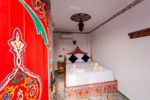 um quarto com uma cama branca e uma parede vermelha em Hotel Chefchaouen em Chefchaouen