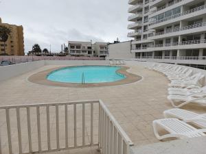 uma grande piscina com espreguiçadeiras brancas ao lado de um edifício em Enjoy Serena Sea View em La Serena