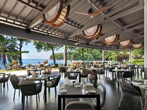 um restaurante com mesas e cadeiras e vista para o oceano em Le Tahiti by Pearl Resorts em Papeete