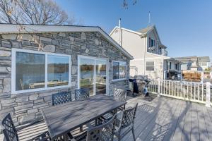 a patio with a wooden table and chairs on a deck at Lakefront Highland Home with Dock about 2 Mi to Milford! 