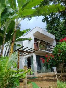 une maison blanche avec un balcon et des arbres dans l'établissement Casa de Praia, à Angra dos Reis