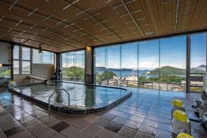 a large swimming pool in a building with windows at Senpokaku in Toba
