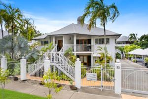 a house with a white fence and palm trees at Oliva St 2 Bedroom Palm Cove Apartment in Palm Cove