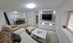 a living room with a couch and a tv on a wall at The Uptown in Strumica