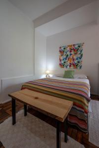 Una cama con una manta colorida y una mesa de madera. en 2 quartos em Ipanema com vista para Lagoa e Cristo, en Río de Janeiro