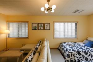 a bedroom with a bed and a table and windows at Kamenoko House - Vacation STAY 15285 in Kadena