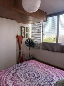 1 dormitorio con 1 cama, ventilador y ventana en Las orquideas en Caraballeda
