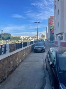 dois carros estacionados numa rua ao lado de uma parede em Appartement à RABAT AGDAL em Rabat