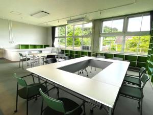 Habitación grande con mesas, sillas y ventanas. en LivingAnywhere Commonsうるま 4bed room - Vacation STAY 65070v, en Uruma