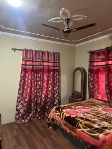 1 dormitorio con cortinas rojas, 1 cama y espejo en Home sleeper en Srinagar