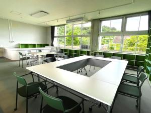 a large room with tables and chairs and windows at LivingAnywhere Commonsうるま twin bed room - Vacation STAY 88989v in Uruma