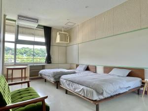 una camera con due letti e una sedia verde di LivingAnywhere Commonsうるま twin bed room - Vacation STAY 88989v a Uruma