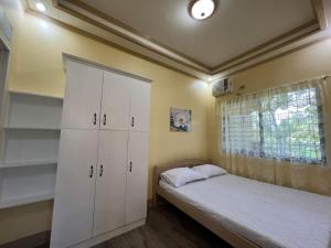 een slaapkamer met een bed en een witte kast bij Nielo Apartment in Dapitan