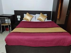 ein großes Bett mit einer roten und gelben Decke in der Unterkunft manjunatha residency in Chikmagalur