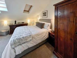 1 dormitorio con 1 cama grande y armario de madera en Rosie Cottage, en Fowey