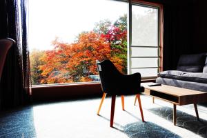 a living room with a chair and a large window at Resort Hotel RAKI House Nasu in Nasu