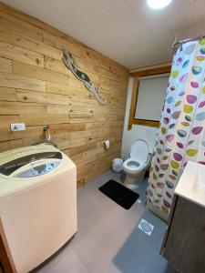 a bathroom with a toilet and a wooden wall at Cabaña El Polux, ruta x-671 in Coihaique