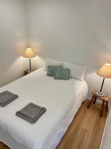 een slaapkamer met een wit bed en 2 lampen bij The Art Gallery Boreen Point in Cootharaba