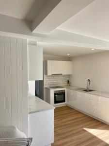 Una cocina blanca con gabinetes blancos y un fregadero. en The Art Gallery Boreen Point, en Cootharaba