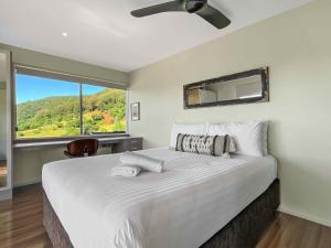 1 dormitorio con 1 cama blanca grande y ventana grande en Elouera Retreat en Mount View