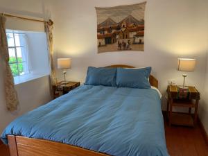 a bedroom with a bed with a blue comforter at Hospedaje Killipata in Cusco