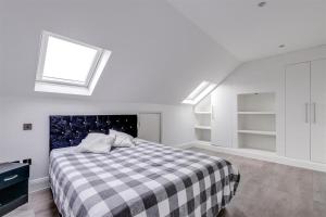 ein Schlafzimmer mit einem Bett mit einer karierten Decke in der Unterkunft Luxurious Hidden Gem in Wandsworth in London