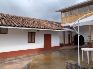 a white building with a brown door and a table at Hospedaje Killipata in Cusco