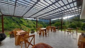eine Terrasse mit Tischen und Stühlen und Aussicht in der Unterkunft AZAHARES HOTEL Y CAFÉ in Manizales