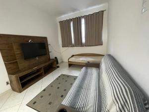uma sala de estar com um sofá e uma televisão de ecrã plano em Casa Pelinca 1 quarto em Campos dos Goytacazes