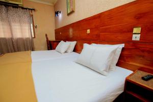 - une chambre avec 2 lits et des oreillers blancs dans l'établissement Hotel Le Prince, à Cotonou