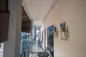 Wisma Merdeka Syariah RedPartner في باليمبانغ: ممر فارغ لمبنى به طاولات وكراسي