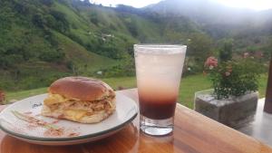 ein Sandwich auf einem Teller neben einem Glas Drink in der Unterkunft AZAHARES HOTEL Y CAFÉ in Manizales
