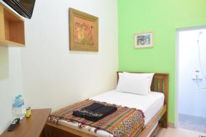 a small bedroom with a bed with a desk at The Cabin Hotel Ambasador in Yogyakarta