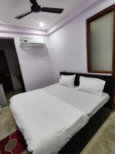 1 dormitorio con 1 cama blanca grande y ventilador de techo en OYO Alpha Guest House Near Bestech Central Square Mall, en Gurgaon